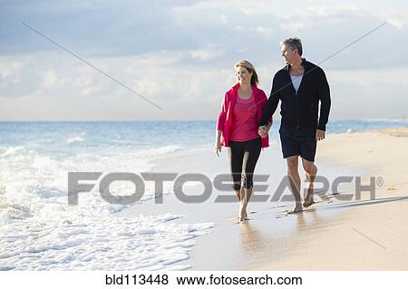 Caucasian couple walking on beach View Large Photo Image Stock Photo - Caucasian couple walking on beach. Fotosearch