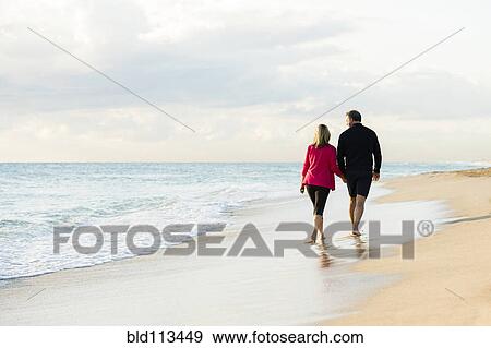 Stock Photo - Caucasian couple walking on beach. Fotosearch