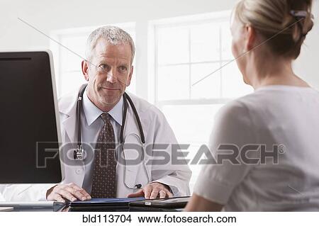 Picture - Caucasian doctor talking with patient. Fotosearch
