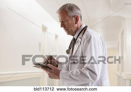 Stock Image - Caucasian doctor using tablet computer. Fotosearch