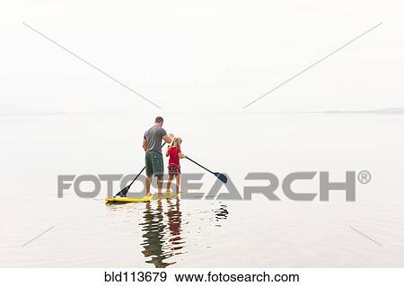 Caucasian father and daughter riding paddle board View Large Photo Image Stock Photo - Caucasian father and daughter riding paddle board. Fotosearch