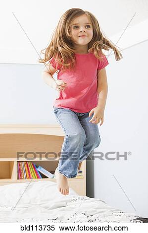 Stock Photography - Caucasian girl jumping on bed. Fotosearch