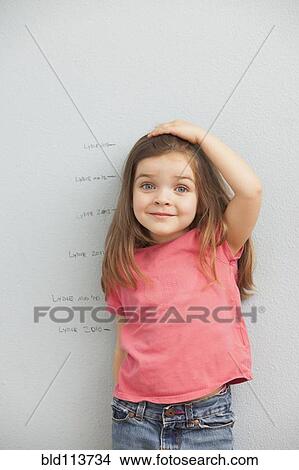 Caucasian girl measuring her height on wall View Large Photo Image Picture - Caucasian girl measuring her height on wall. Fotosearch