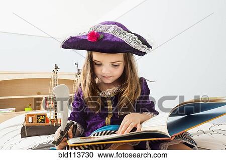Stock Image - Caucasian girl reading book on bed. Fotosearch