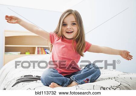 Stock Image - Caucasian girl sitting on bed. Fotosearch