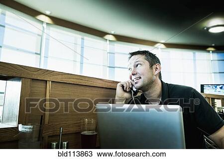 Caucasian man on cell phone using laptop View Large Photo Image Stock Image - Caucasian man on cell phone using laptop. Fotosearch