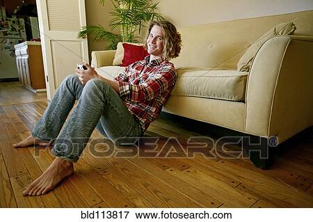 Caucasian man playing video games in living room View Large Photo Image Stock Photo - Caucasian man playing video games in living room. Fotosearch