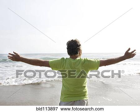 Stock Photo - Caucasian man standing on beach. Fotosearch