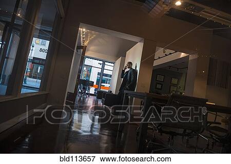 Stock Photo - Caucasian man talking on cell phone in hallway. Fotosearch