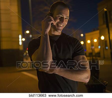 Stock Image - Caucasian man talking on cell phone on city street. Fotosearch