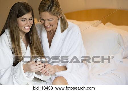 Stock Photo - Caucasian mother and daughter using cell phone. Fotosearch