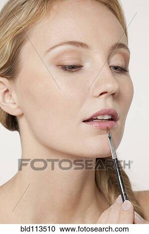 Stock Image - Caucasian woman applying makeup. Fotosearch