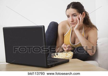 Caucasian woman eating popcorn at laptop View Large Photo Image Stock Image - Caucasian woman eating popcorn at laptop. Fotosearch