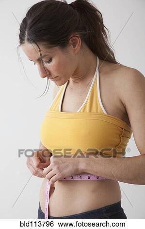 Stock Photograph - Caucasian woman measuring her waistline. Fotosearch