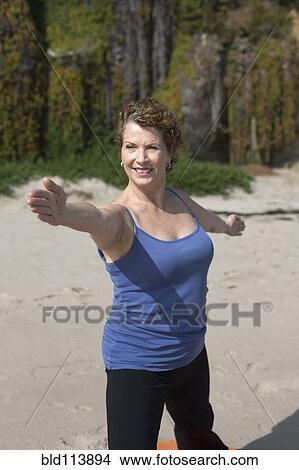 Picture - Caucasian woman practicing yoga on beach. Fotosearch