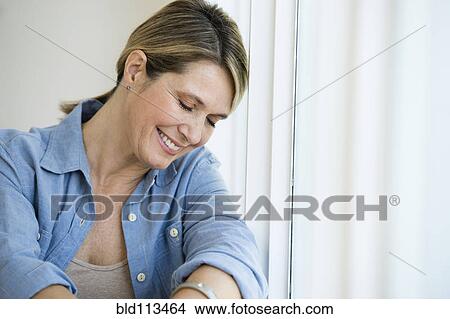 Picture - Caucasian woman smiling in window. Fotosearch