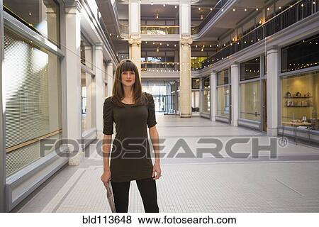 Stock Photo - Caucasian woman standing in shopping mall. Fotosearch