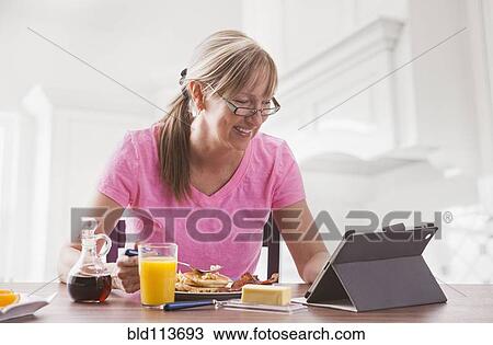 Caucasian woman using tablet computer at breakfast View Large Photo Image Stock Image - Caucasian woman using tablet computer at breakfast. Fotosearch
