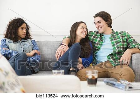 Picture - Couple ignoring friend on sofa. Fotosearch