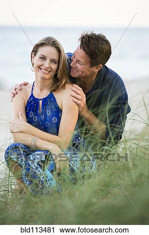 Couple smiling together on beach View Large Photo Image Stock Image - Couple smiling together on beach. Fotosearch
