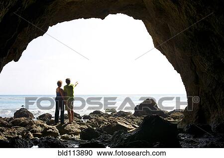 Couple standing in rocky beach cave View Large Photo Image Stock Image - Couple standing in rocky beach cave. Fotosearch