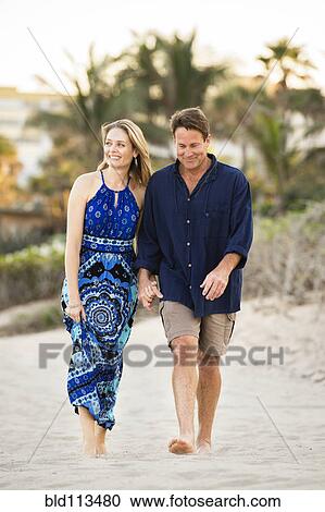 Stock Image - Couple walking together on beach. Fotosearch
