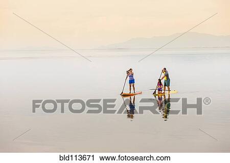 Family riding paddle boards View Large Photo Image Stock Image - Family riding paddle boards. Fotosearch