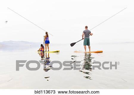 Family riding paddle boards View Large Photo Image Stock Image - Family riding paddle boards. Fotosearch