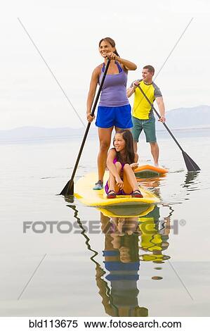 Family riding paddle boards View Large Photo Image Stock Photography - Family riding paddle boards. Fotosearch