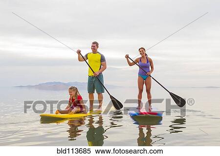 Family riding paddle boards View Large Photo Image Stock Photography - Family riding paddle boards. Fotosearch