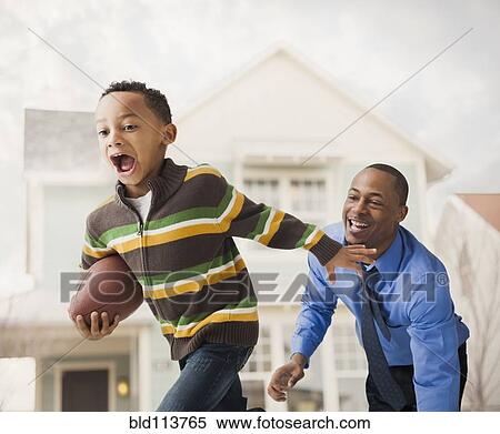 Stock Photography - Father and son playing football. Fotosearch