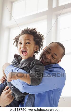 Stock Image - Father and son playing indoors. Fotosearch