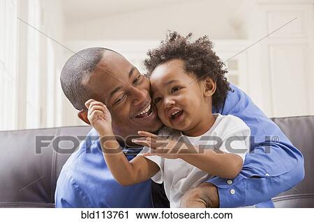 Stock Image - Father and son relaxing on sofa. Fotosearch