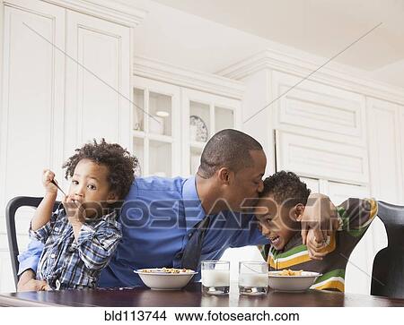 Picture - Father kissing sons at breakfast table. Fotosearch