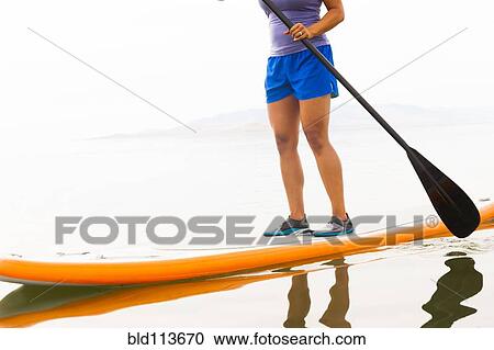 Stock Image - Filipino woman riding paddle board. Fotosearch
