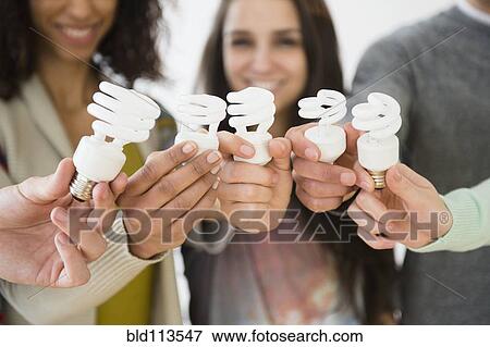 Friends holding fluorescent light bulbs View Large Photo Image Stock Photo - Friends holding fluorescent light bulbs. Fotosearch