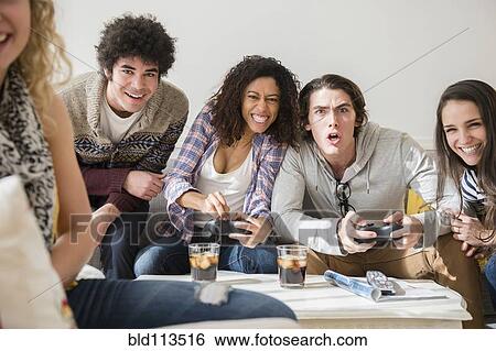 Stock Photograph - Friends playing video games in living room. Fotosearch