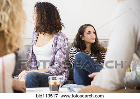 Stock Photo - Friends relaxing in living room. Fotosearch