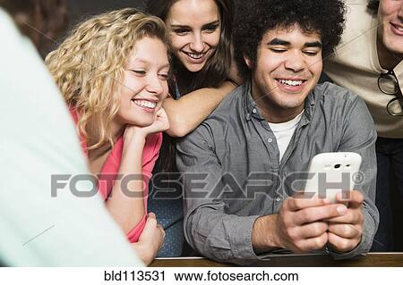 Friends using cell phone together View Large Photo Image Stock Image - Friends using cell phone together. Fotosearch