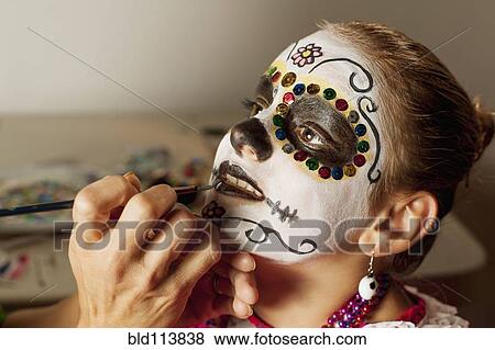 Stock Photo - Girl having face painted for Dia de los Muertos. Fotosearch