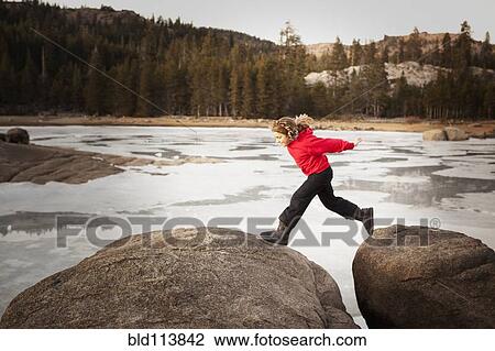 Stock Image - Girl playing on boulders. Fotosearch