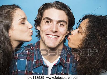 Stock Photo - Girls kissing man's cheeks. Fotosearch