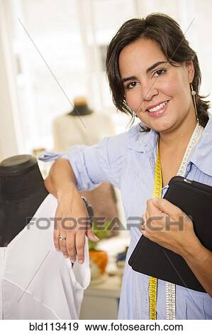 Stock Photo - Hispanic dressmaker smiling in studio. Fotosearch