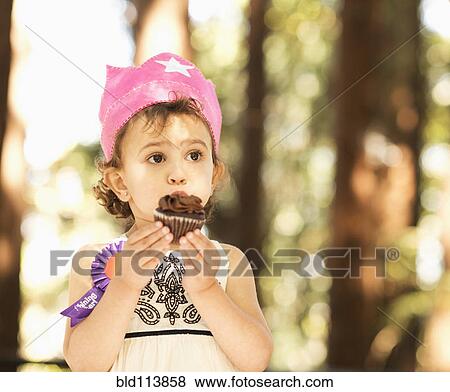 Hispanic girl eating cupcake outdoors View Large Photo Image Stock Photo - Hispanic girl eating cupcake outdoors. Fotosearch