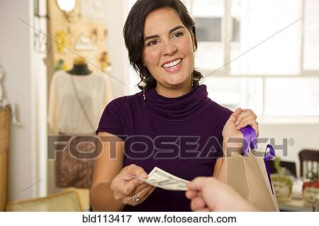 Stock Photo - Hispanic woman shopping with cash. Fotosearch