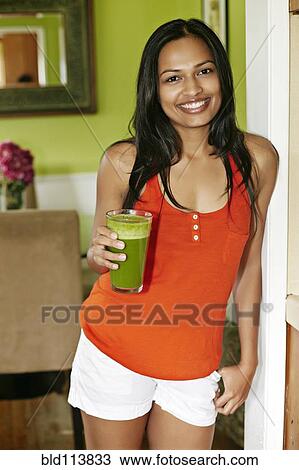 Stock Image - Indian woman having glass of juice. Fotosearch