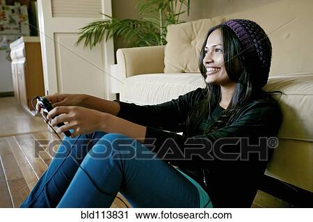 Stock Image - Indian woman playing video games in living room. Fotosearch