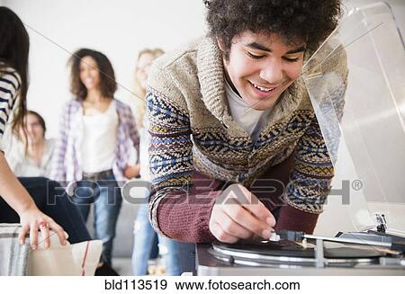 Stock Photo - Man putting on record in living room. Fotosearch