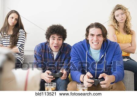 Stock Image - Men with video games ignoring girlfriends. Fotosearch