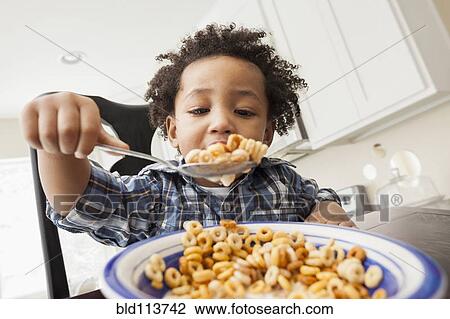 Stock Image - Mixed race boy eating at table. Fotosearch